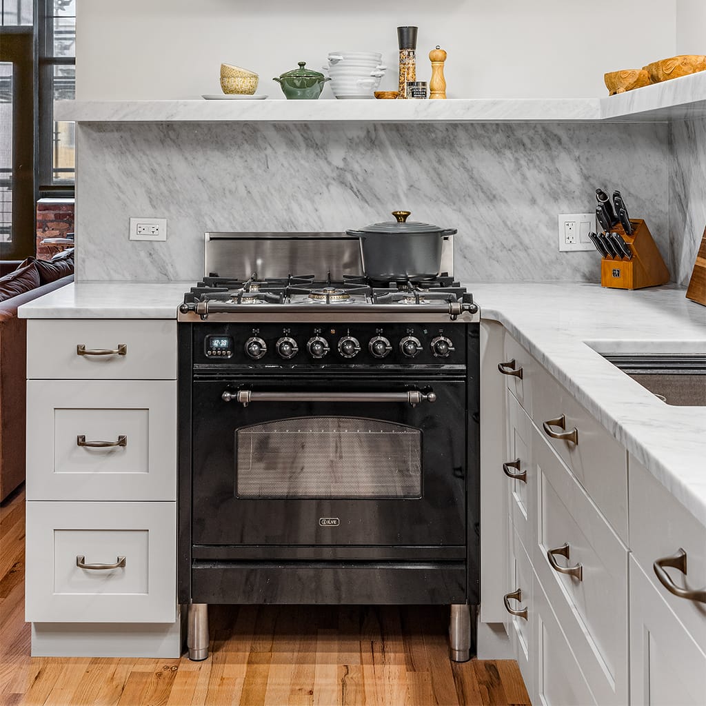 Image of a dark range surrounded by white kitchen counters and shelves